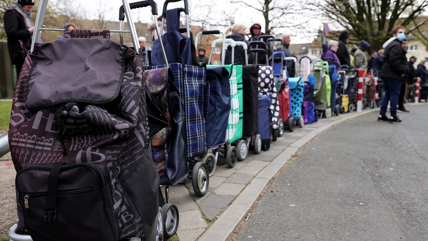 epa08332035 People wait outside the food distribution centre of the non-profit food bank 'Tafel' in Essen, Germany, 30 March 2020. The German government and local authorities are heightening ...