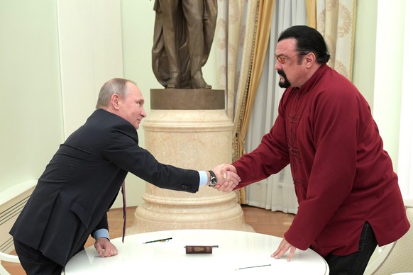 epa05647257 Russian President Vladimir Putin (L) shakes hands with US actor Steven Seagal (R) at the Kremlin in Moscow, Russia, 25 November 2016. The Russian President handed a Russian passport to Sea ...