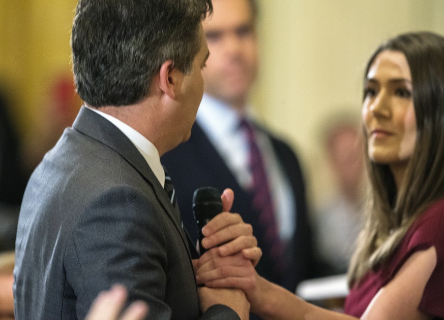 epa07149741 CNN reporter Jim Acosta (L) holds onto a microphone asn an aide tries to take it away during a press conference with US President Donald J. Trump in the East Room of the White House in Was ...