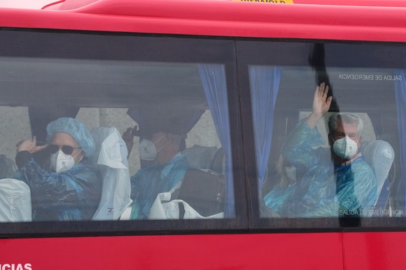 Passengers wave inside a bus after being disembarked from the hantavirus-stricken cruise ship MV Hondius at the port of Granadilla in Tenerife, Canary Islands, Spain, Sunday, May 10, 2026. (AP Photo/M ...