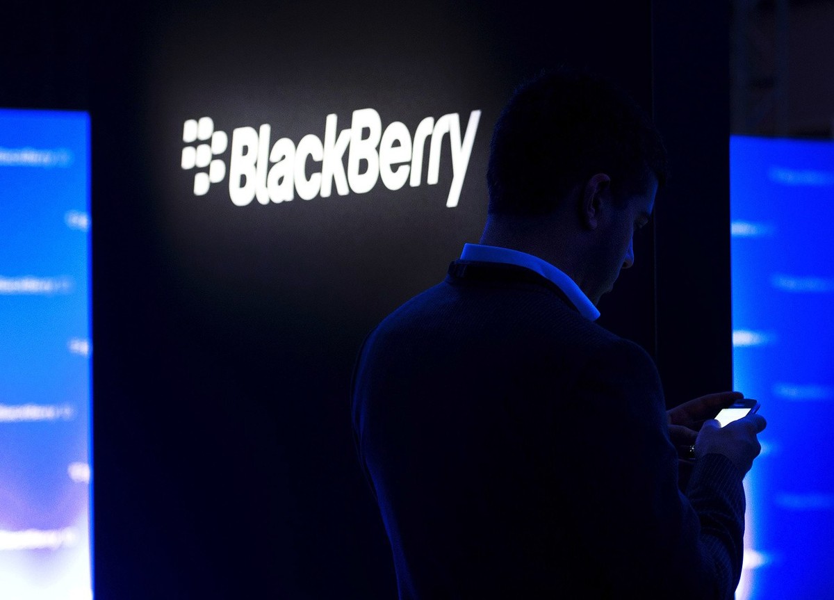 FILE - In this Wednesday, Jan. 30, 2013, file photo, a man uses his Blackberry as people wait for the Blackberry BB10 launch in Toronto. Fairfax Financial Holdings has offered to buy BlackBerry in a d ...