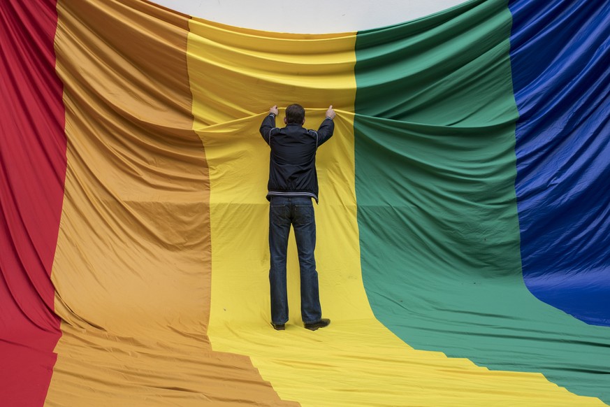 Swiss LGBT activists prepare a flag during a vigil for those killed and wounded in the Sunday June 12, mass shooting at a gay nightclub in Orlando, at a church in Zuerich, Switzerland, Monday, June 13 ...