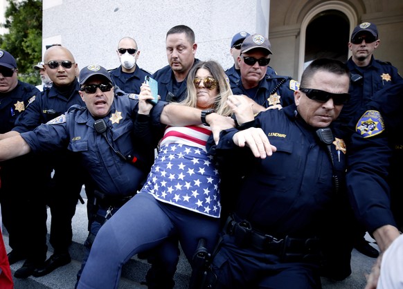 FILE - In this May 1, 2020, file photo, a protester is detained by California Highway Patrol officers during a demonstration against Gov. Gavin Newsom&#039;s stay-at-home orders due to the coronavirus ...