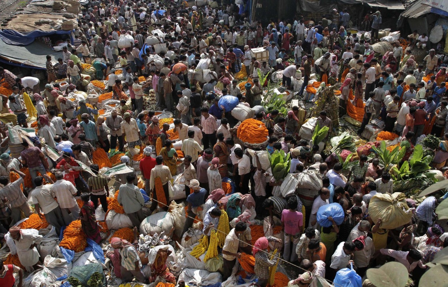 ARCHIV: Menschen sammeln sich auf einem Markt in Kalkutta (Indien) und verkaufen Ringelblumen und andere Blumen (Foto vom 05.11.10). Die Weltbevoelkerung wird mit 6,97 Milliarden Menschen zu Beginn na ...