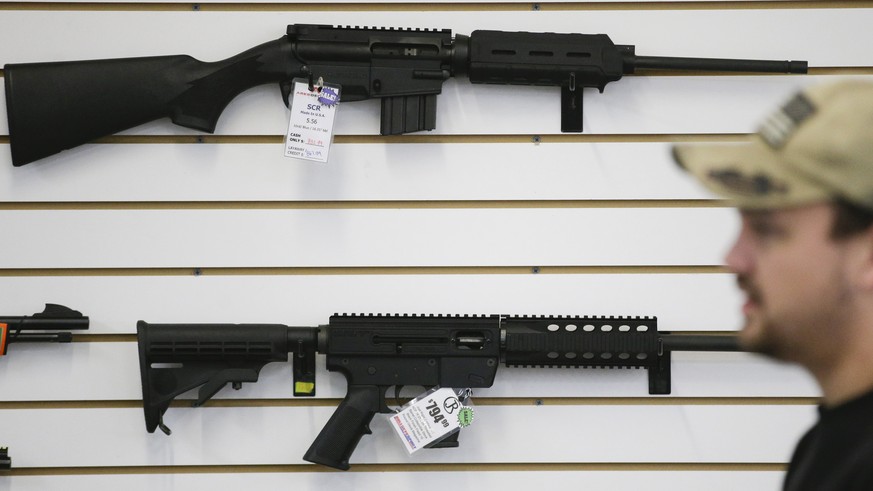 In this Dec. 9, 2015, photo, a sales associate walks past semiautomatic rifles at Bullseye Sport gun shop in Riverside, Calif. The massacre at Sandy Hook elementary school in which a mentally disturbe ...
