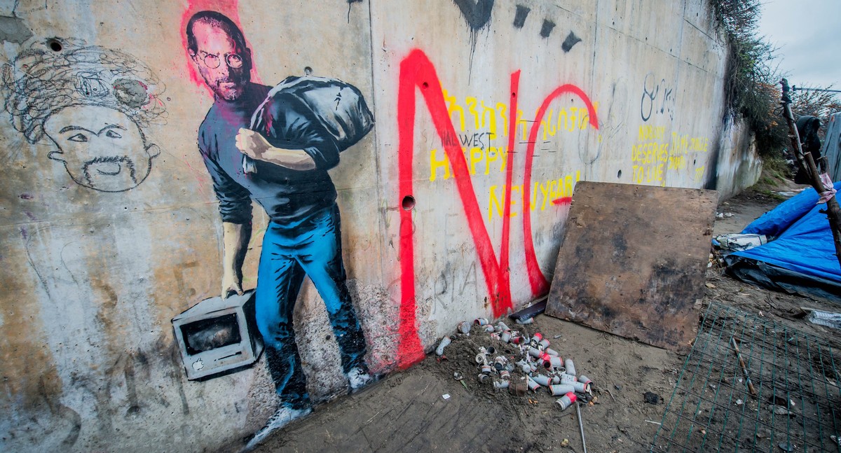 epa05080941 A tag of the artist Banksy representative Steve Jobs in the camp called 'The Jungle' in the port of Calais, France, 25 December 2015. By this Banksy tag means that Steve Jobs was ...
