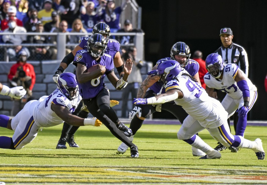 BALTIMORE, MD - NOVEMBER 07: Baltimore Ravens quarterback Lamar Jackson 8 runs with the ball and tries to avoid Minnesota Vikings middle linebacker Eric Kendricks 54 and defensive tackle Armon Watts 9 ...