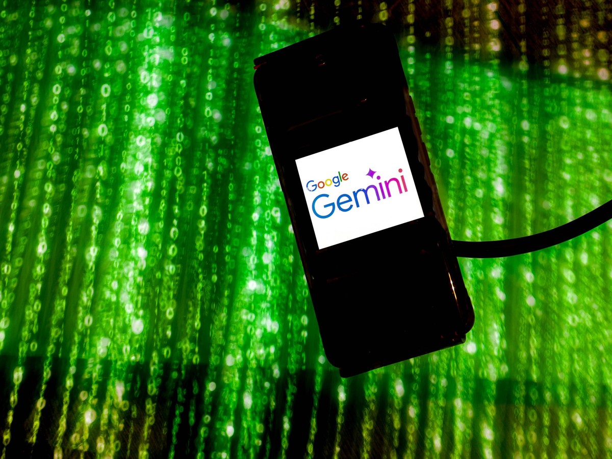 AI Industry Competes In The Market In this photo illustration the Google Gemini logo is shown on a mobile phone screen against an illustration of 0:1 matrix as artificial intelligence industry races t ...