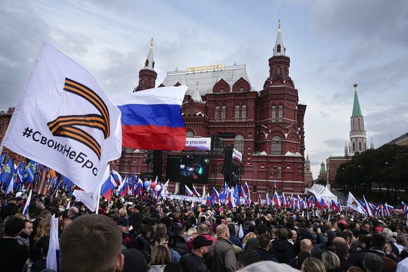 FILE - Demonstrators hold Russian state flags and flags with with the letter Z, which has become a symbol of the Russian military, and a hashtag reading &quot;We don&#039;t abandon our own&quot; durin ...