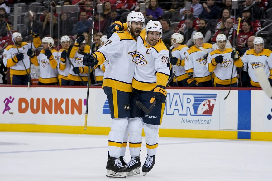 Nashville Predators defenseman Roman Josi (59) celebrates his goal on New Jersey Devils goaltender Akira Schmid (40) with defenseman Ben Harpur (17) during the second period of an NHL hockey game Frid ...