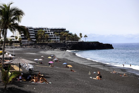epa11484967 Tourists and bathers spend their time on the authorized part of the beach in Puerto Naos, La Palma, Canary Islands, Spain, 16 July 2024 (issued 18 July 2024). The once vibrant tourist cent ...