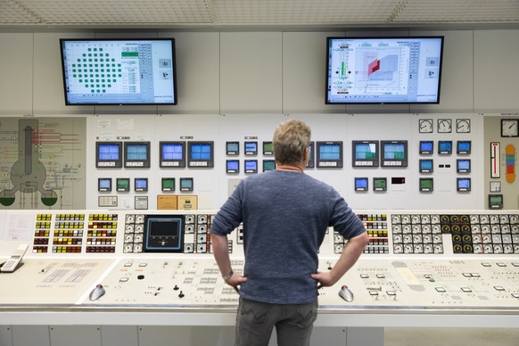 epa08083327 The reactor operator checks his instruments and screens in the control room after pushing the buttons to power down the reactor during the official shutdown of the Muehleberg nuclear power ...