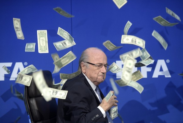 epa09886194 (FILE) In file photo FIFA president Sepp Blatter is photographed while banknotes thrown by British comedian Simon Brodkin hurtle through the air during a press conference following the ext ...