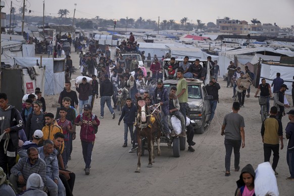Palestinians carry bags filled with food and humanitarian aid provided by the Gaza Humanitarian Foundation, a U.S.-backed organization approved by Israel, in Khan Younis, southern Gaza Strip, on Tuesd ...