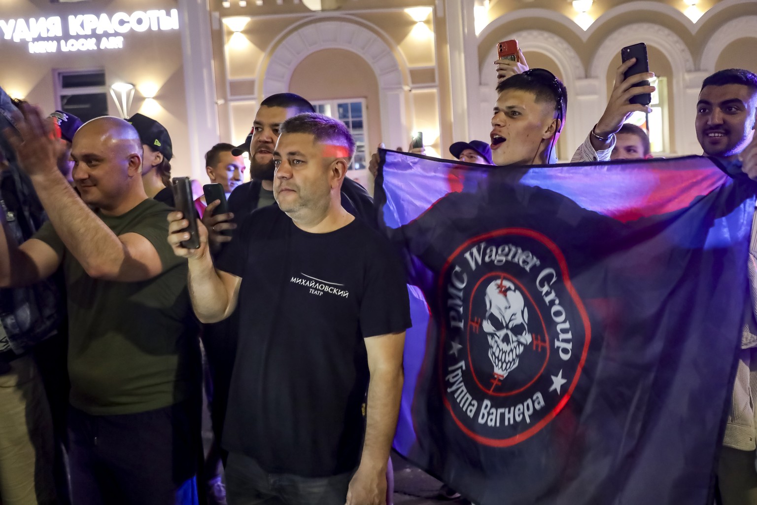 People shout and wave a flag of the military company Wagner Group at soldiers before leaving an area near the headquarters of the Southern Military District in Rostov-on-Don, Russia, Saturday, ...