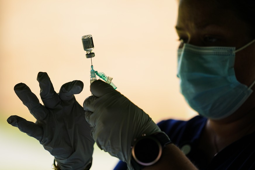 FILE - In this Sept. 14, 2021, file photo, a syringe is prepared with the Pfizer COVID-19 vaccine at a clinic at the Reading Area Community College in Reading, Pa. Companies with at least 100 workers  ...