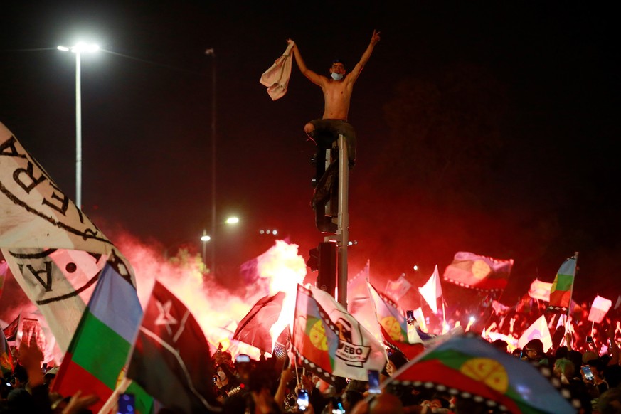 epa08774106 Dozens of people celebrate after learning about the partial results of the constitutional referendum, which indicates the crafting of a new constitution, in Santiago, Chile, 25 October 202 ...