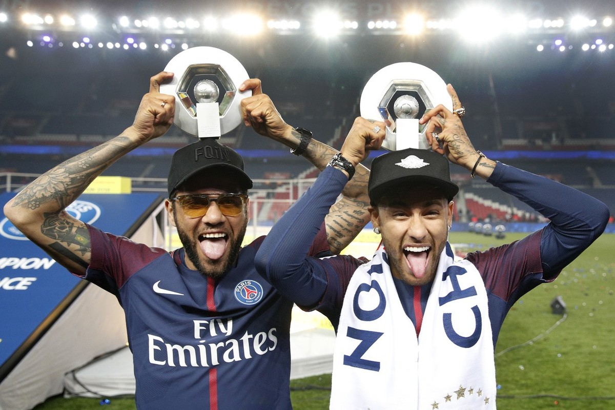 PSG players Neymar, right, and Dani Alves hold their League One winners trophy after the soccer match between Paris Saint-Germain and Stade Rennais at the Parc des Princes stadium in Paris, Saturday M ...