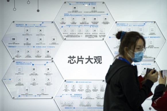 A visitor takes a photo near a display of semiconductors and computer chips from Tsinghua Unigroup at the China Beijing International High-Tech Expo in Beijing, Saturday, Sept. 25, 2021. The annual ex ...