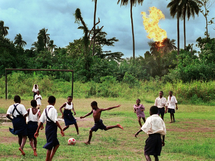 390464 19: Children in the Nigerian village of Akaraolu play soccer at recess while the nearby Oshie gas flare roars on. No one under the age of 30 in the village can remember a time before what they  ...