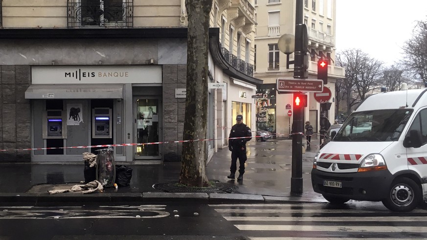 A police officer guards the Milleis bank after a robbery in Paris, Tuesday, Jan.22, 2019. Paris police say several suspects are on the run after they robbed the bank on the Champs-Elysees in broad day ...