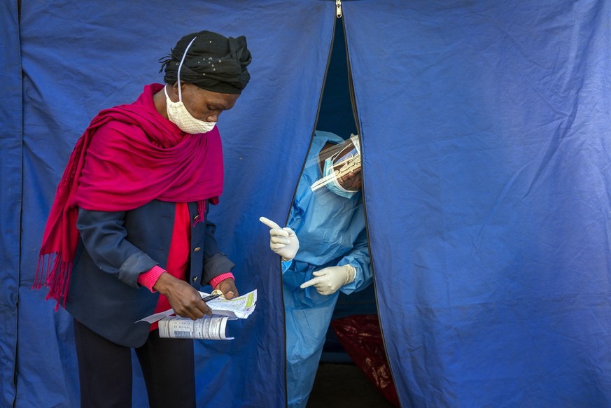 Heath officials check the listings of people who are to be tested for COVID-19 as well as HIV and Tuberculosis, in downtown Johannesburg Thursday, April 30, 2020. Thousands are being tested in an effo ...