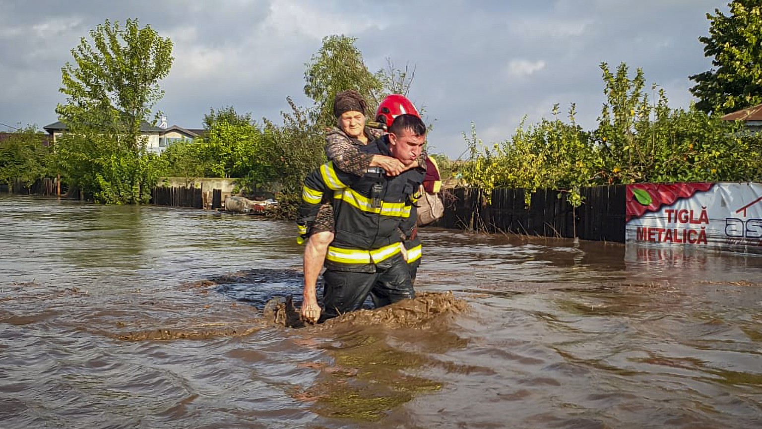 In this photo released by the Romanian Emergency Services Galati (ISU Galati), a rescuer carries a woman in Pechea, Romania, Saturday, Sept. 14, 2024 after torrential rainstorms left scores of people  ...