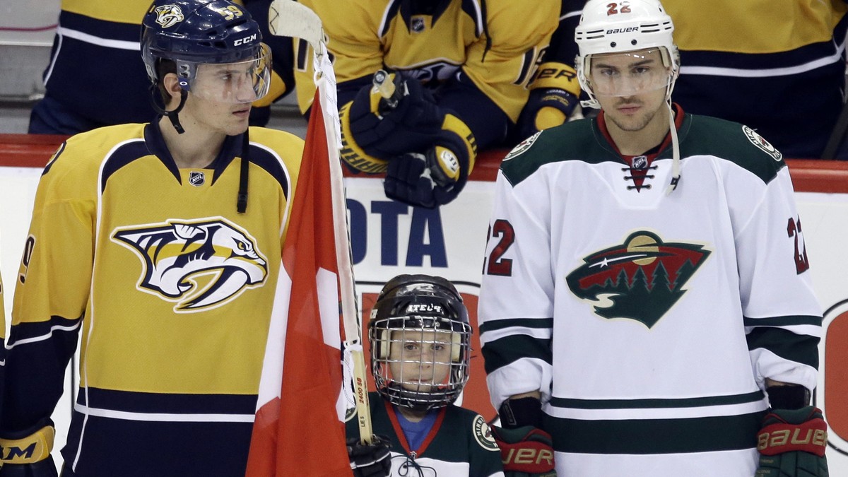 A young flag bearer holds a Swiss flag as Nashville Predators' Simon Moser, left, and Nashville Predators' Roman Josi were honored along with Minnesota Wild's Nino Niederreiter, right,  ...
