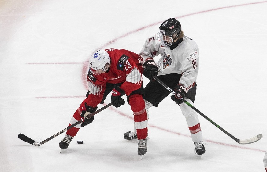 Swiss Cedric Fiedler (23) and Austrian Finn Van Ee (26) compete with the puck during the second period of the IIHF World Junior Hockey Championships leading up to the competition in Edmonton, Alberta, OR...