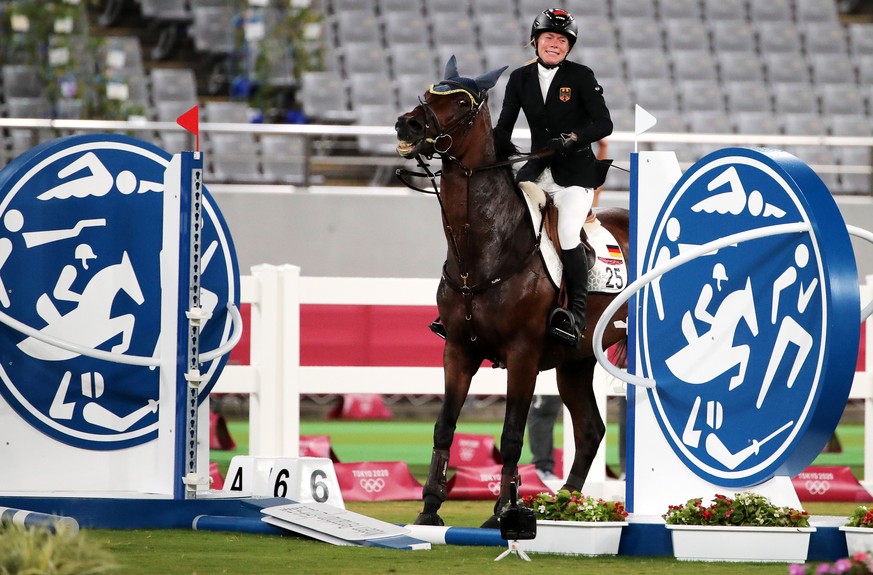 epa09400054 Annika Schleu of Germany on Saint Boy after hitting an obstacle as they compete in the Show Jumping portion of the Modern Pentathlon event at the Tokyo 2020 Olympic Games at the Tokyo Stad ...