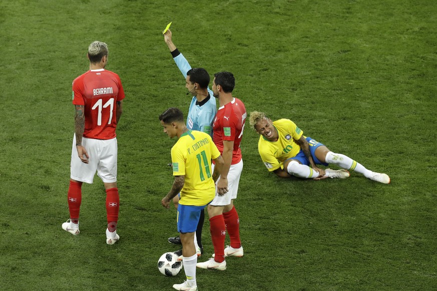 Mexican referee Cesar Arturo Ramos, center, shows the yellow card to Switzerland's Valon Behrami, left, as Brazil's Neymar reacts during the group E match between Brazil and Switzerland at t ...