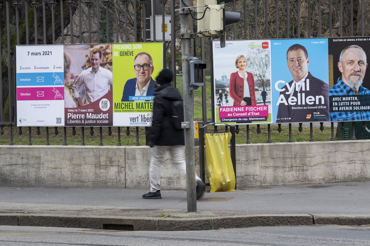 Une personne passe devant les affiches des candidats pour l'election complementaire d'un membre du Conseil d'Etat, avec les portraits sur les affiches de Pierre Maudet, du parti Liberte ...
