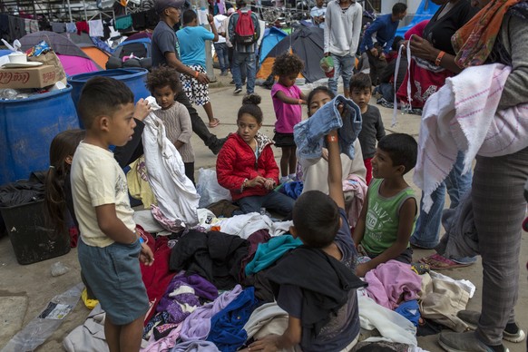 Central American migrant children look through a pile of donated clothes at the Benito Juarez Sports Center serving as a temporary shelter for Central American migrants, in Tijuana, Mexico, Saturday,  ...