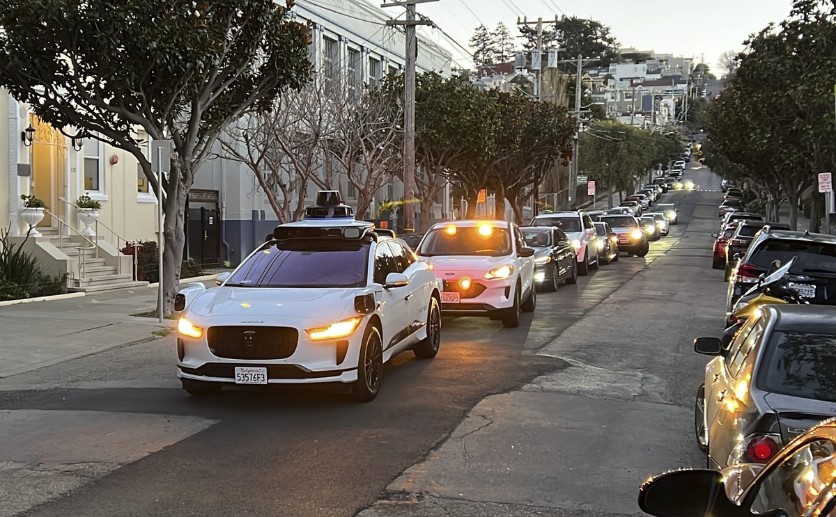 A Waymo driverless taxi stops on a street in San Francisco for several minutes because the back door was not completely shut, while traffic backs up behind it, on Feb. 15, 2023. Cruise, a subsidiary o ...