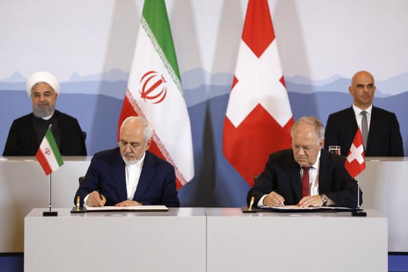 epa06860628 Swiss Federal Councillor Johann Schneider-Ammann (front, R) and Iranian Minister of Foreign Affairs Mohammad Javad Zarif (front, L) sign a letter of intent in presence of Swiss Federal Pre ...