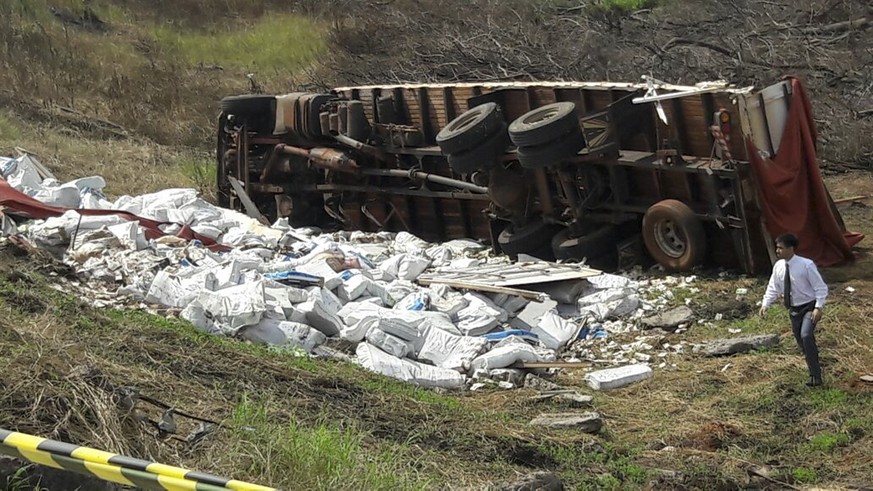 A man walks by some 30 tons of Venezuelan currency that fell from an overturned truck near San Estanislao, 220 kilometers (136 miles) north of Asuncion, Paraguay, on Wednesday, Feb. 15, 2017. The mone ...