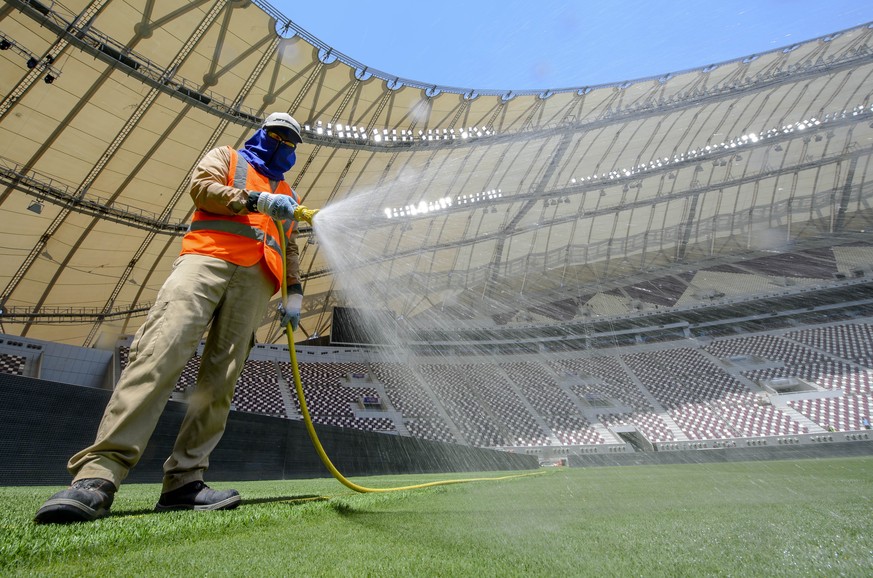 epa10253972 Photo taken on 16 May 2017 of ground maintenance staff watering the pitch inside the Khalifa International Stadium in Doha, Qatar. The 45,416- seater venue will host 6 group stage matches, ...