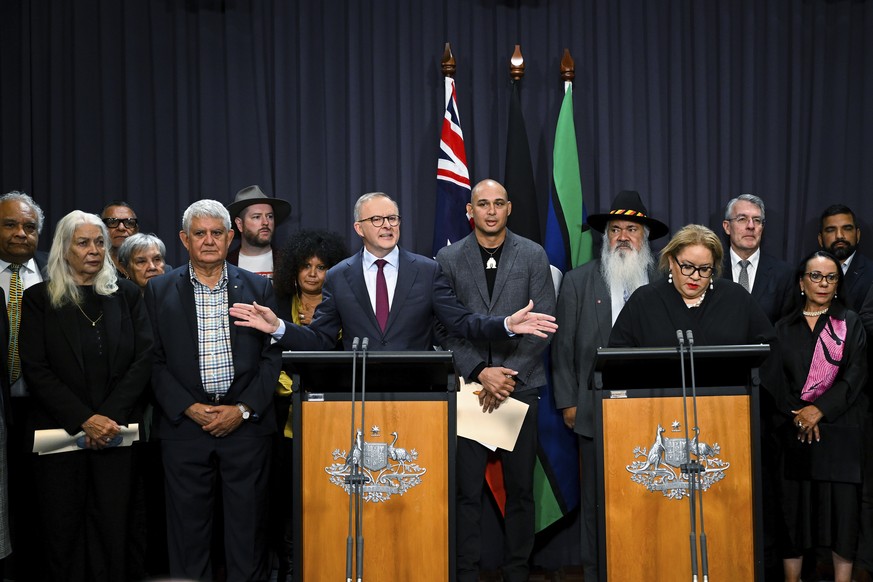 Australian Prime Minister Anthony Albanese, at the left podium, is surrounded by members of the First Nations Referendum Working Group as he speaks during a press conference at Parliament House in Can ...