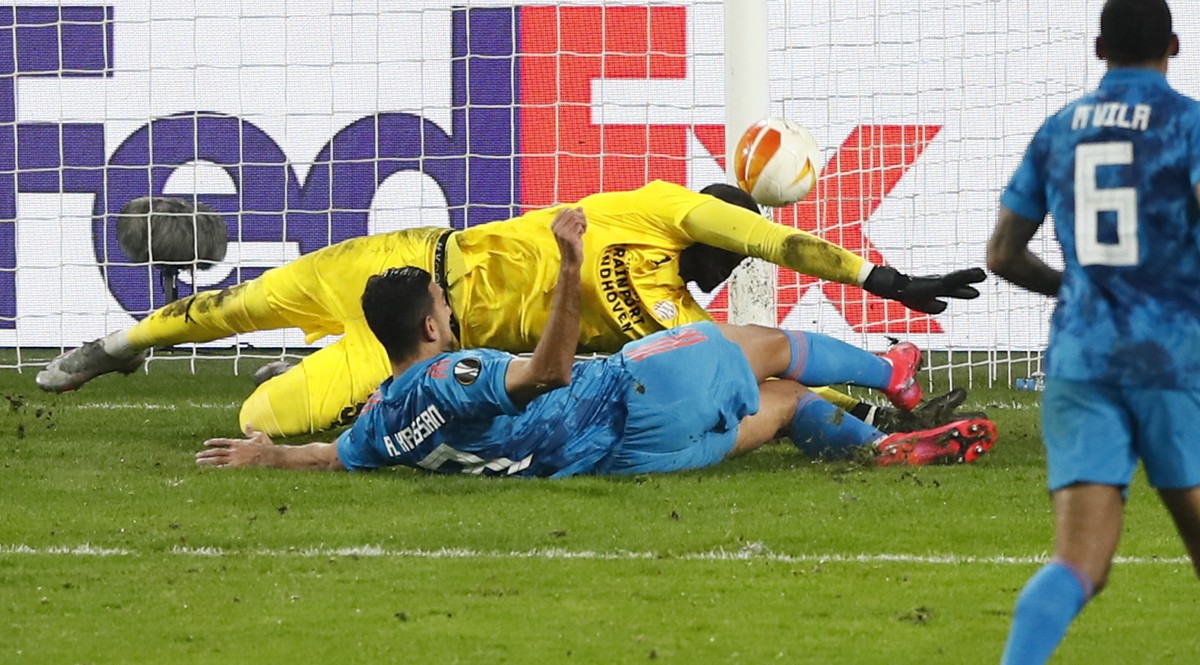 Olympiacos' Ahmed Hassan scores his side's first goal passing =PSV's goalkeeper Yvon Mvogo, in yellow, during the Europa League round of 32 second leg soccer match between PSV and Olymp ...