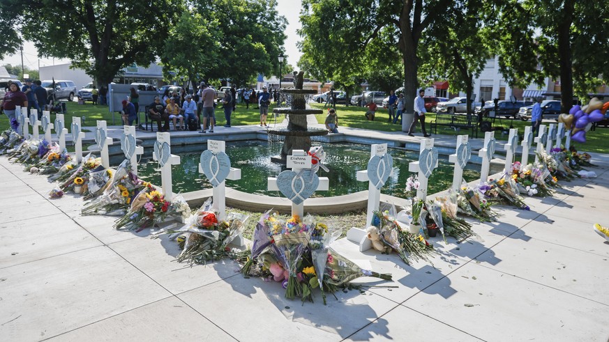 epa09978804 People leave flowers and sign messages on crosses bearing the names of victims in the city park following a mass shooting at the Robb Elementary School in Uvalde, Texas, USA, 26 May 2022.  ...