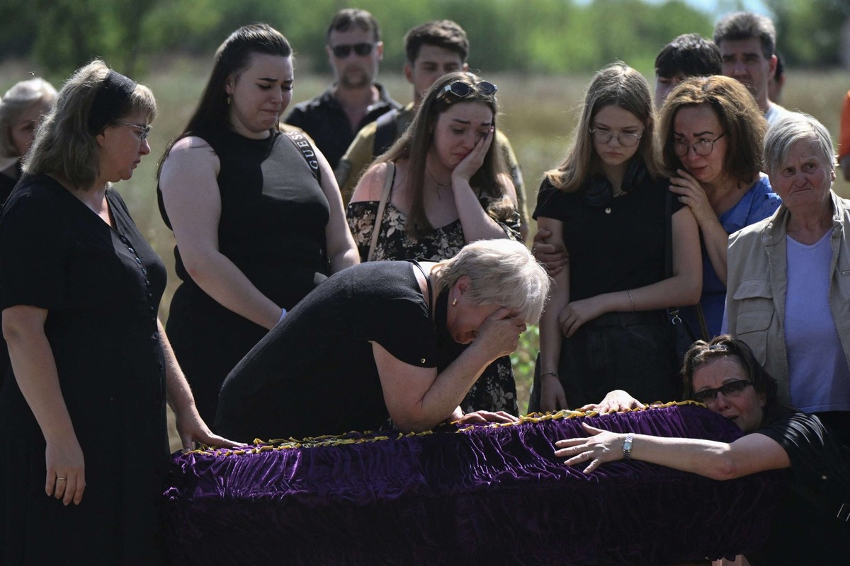 Des proches et des amis pleurent devant un cercueil lors des funérailles de Mykyta et Sofia Lamekhov et de leur fils Lev dans un cimetière de Sloviansk.