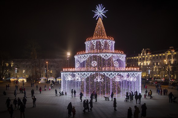 Visitors walk in front of the illuminated Christmas tree at Cathedral Square in Vilnius, Lithuania, Friday, Dec. 2, 2022. (AP Photo/Mindaugas Kulbis)
