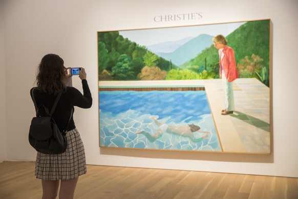 A Christie's employee take a cell phone photo of David Hockney's "Portrait of an Artist (Pool with Two Figures)," Thursday, Sept. 13, 2018, in New York. One of the British artist&# ...