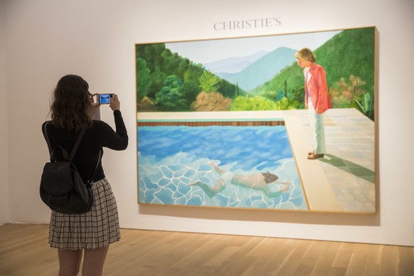 A Christie&#039;s employee take a cell phone photo of David Hockney&#039;s &quot;Portrait of an Artist (Pool with Two Figures),&quot; Thursday, Sept. 13, 2018, in New York. One of the British artist&# ...