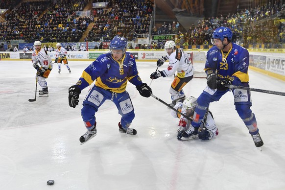 Tino Kessler, links, und Samuel Walser, rechts, von Davos, gegen Dominik Schlumpf von Zug, unten, beim zweiten Playoff-Halbfinalspiel der National League A zwischen dem HC Davos und EV Zug, am Donners ...