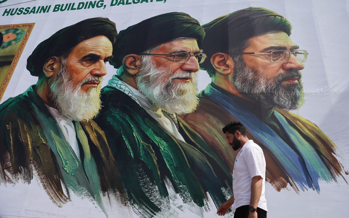epa12907239 A man walks past a billboard featuring the portraits of Iran's new Supreme Leader Ayatollah Mojtaba Khamenei, the late Supreme Leader Ayatollah Ali Khamenei, and the late Supreme Lead ...