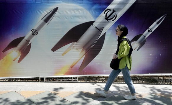 FILE - A woman walks past a banner showing missiles being launched, in northern Tehran, Iran, April 19, 2024. Secretary of State Antony Blinken and national security adviser Jake Sullivan said Friday, ...