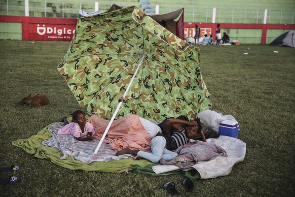 People rest after spending the night at a soccer field following Saturday� ?s 7.2 magnitude earthquake in Les Cayes, Haiti, Sunday, Aug. 15, 2021. (AP Photo/Joseph Odelyn)