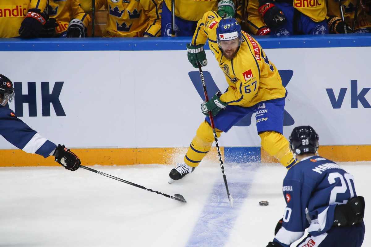 Sweden's Linus Omark, center, controls the puck during the Ice Hockey Channel One Cup match between Finland and Sweden in Moscow, Russia, Saturday, Dec. 17, 2016. (AP Photo/Pavel Golovkin)