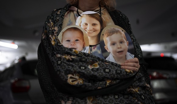 A woman holds a mask depicting the faces of Shiri Bibas and her sons Kfir and Ariel, Israelis who are being held hostage in the Gaza Strip by the Hamas militant group, during a protest demanding the r ...